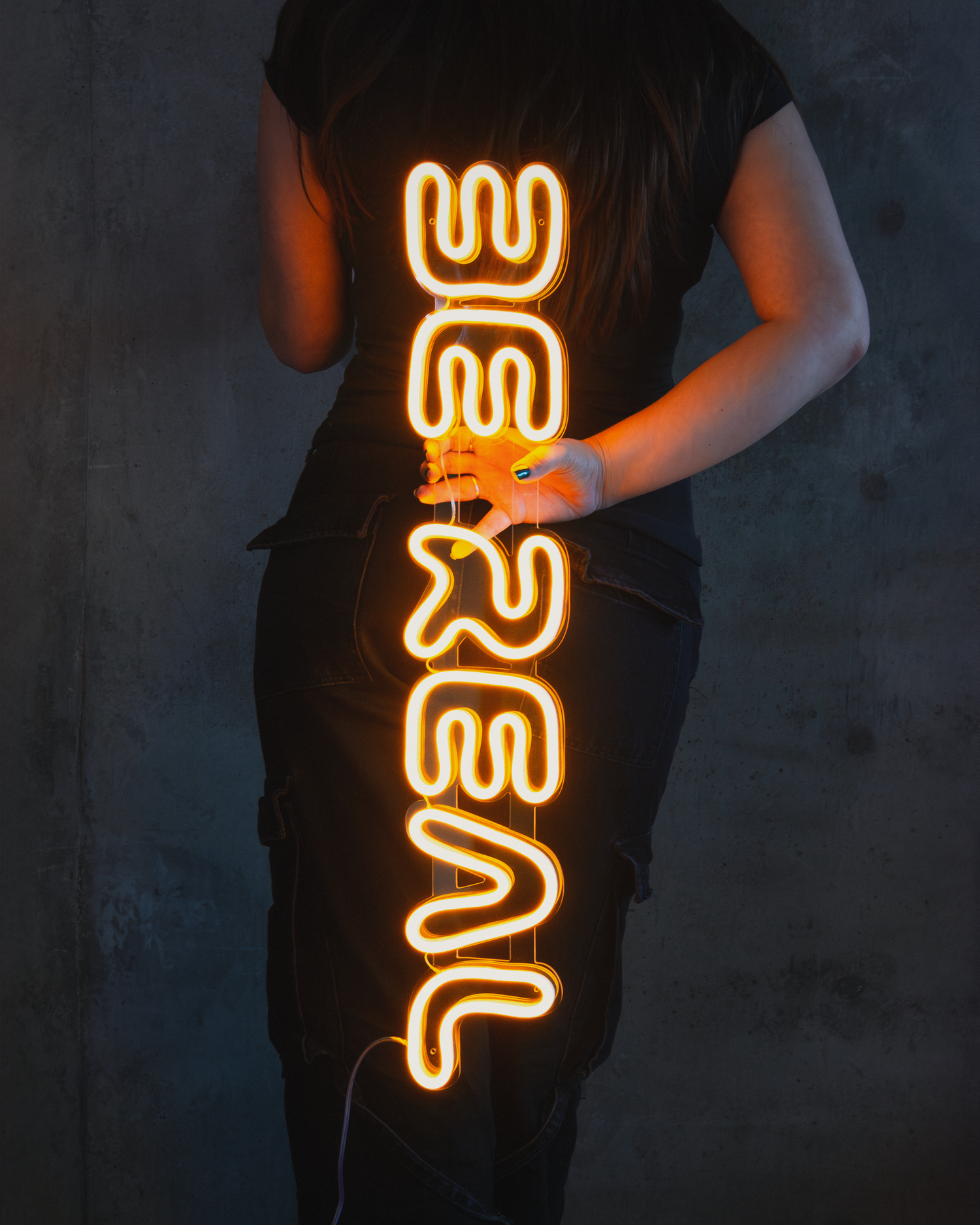 Girl holding a custom neon sign that says "be real"