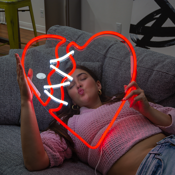 A girl holding a broken heart neon sign