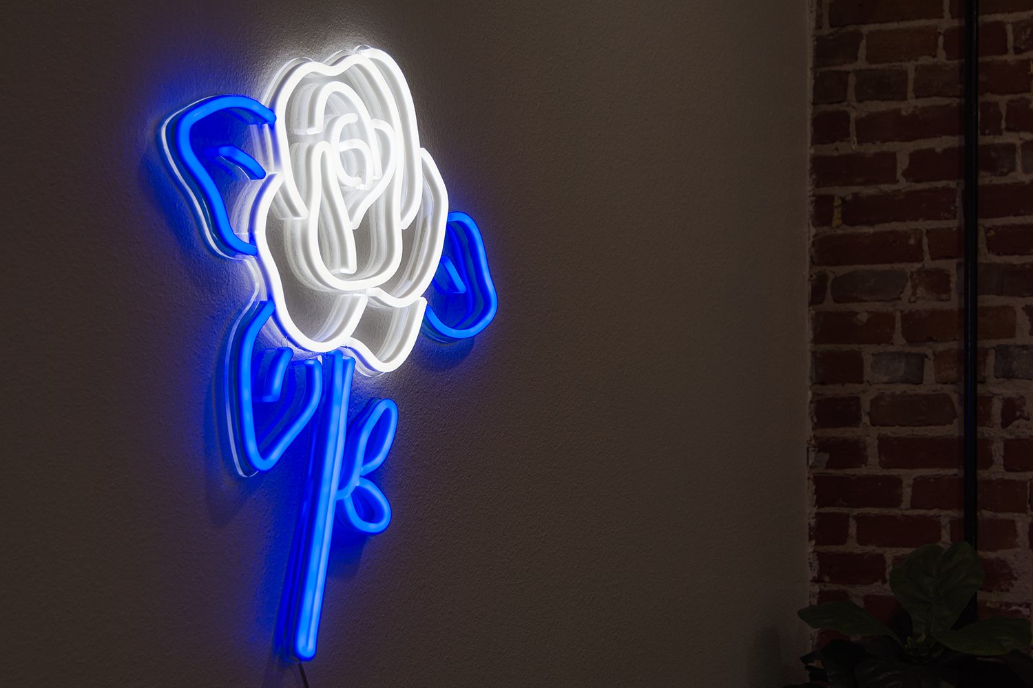 A blue flower neon sign on a brick wall