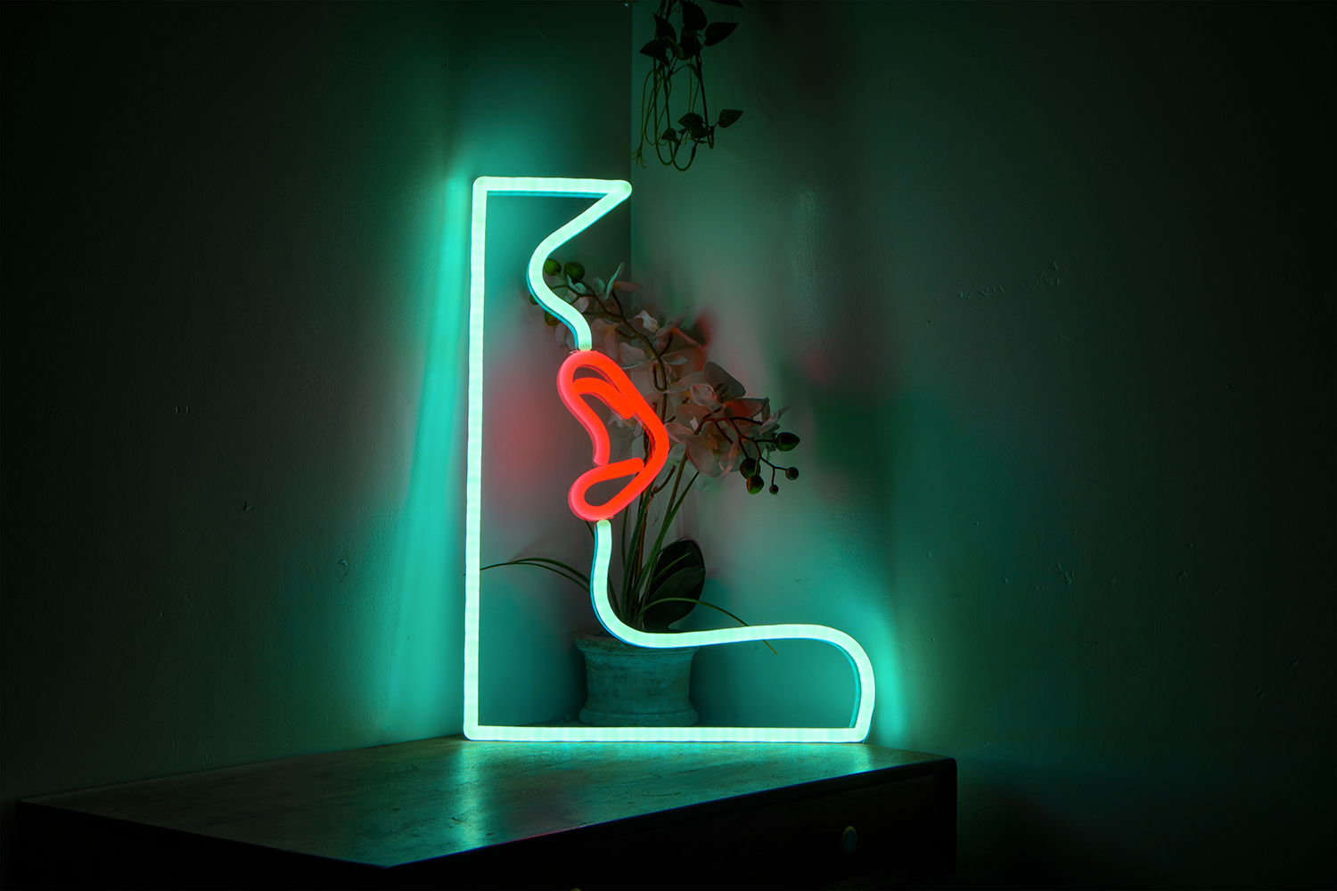A light blue and red neon sign of a woman's lips sat on a table in a dark room