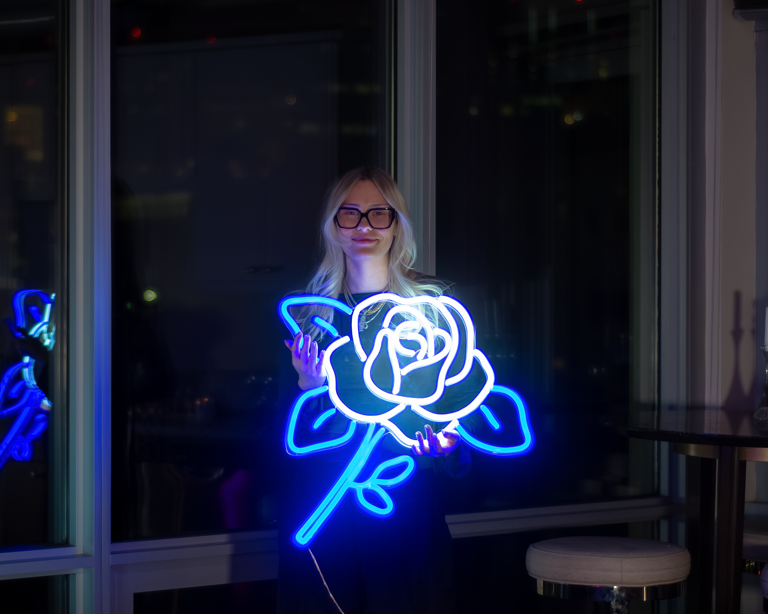 A woman holding a flower neon sign