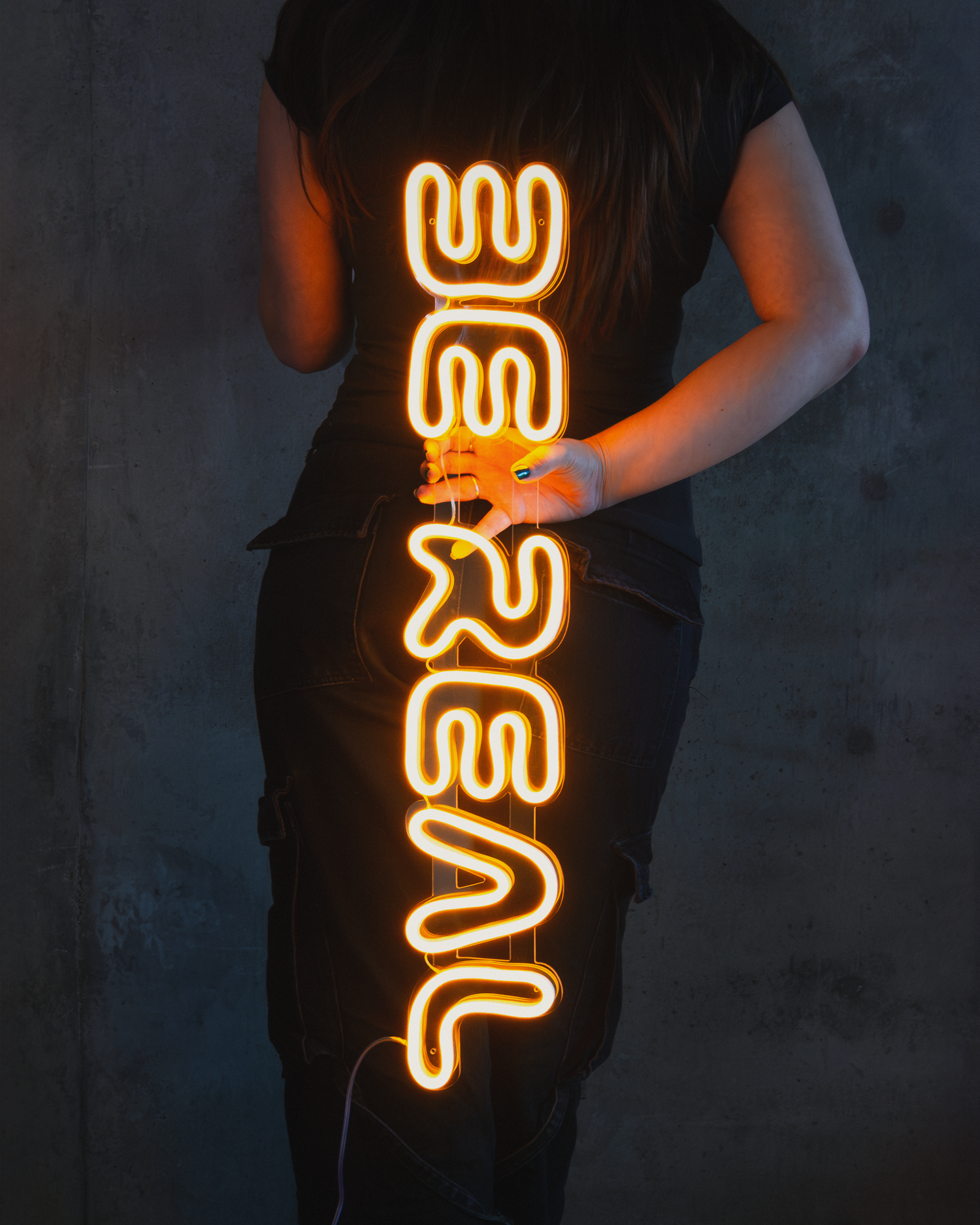 Girl holding a neon sign that says "be real"