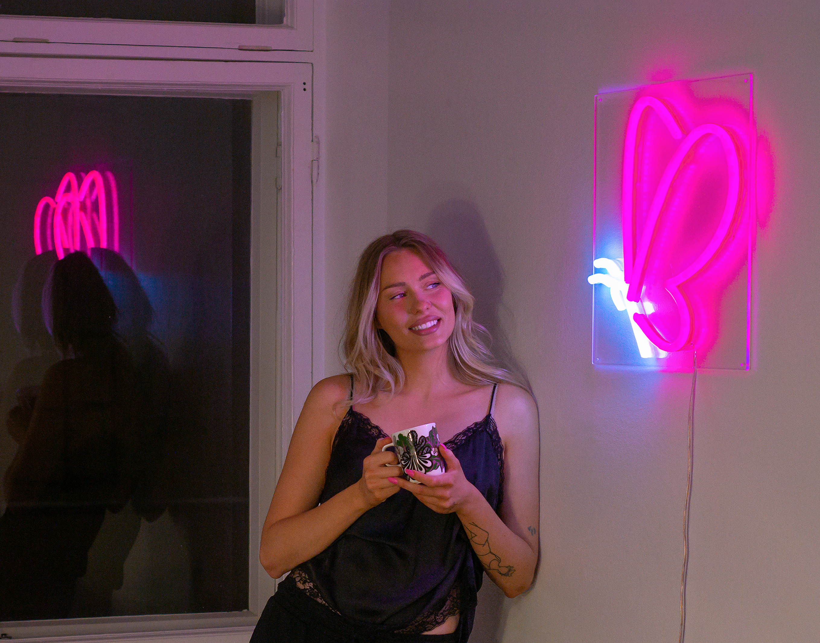 A girl smiling at a white and pink butterfly neon sign.