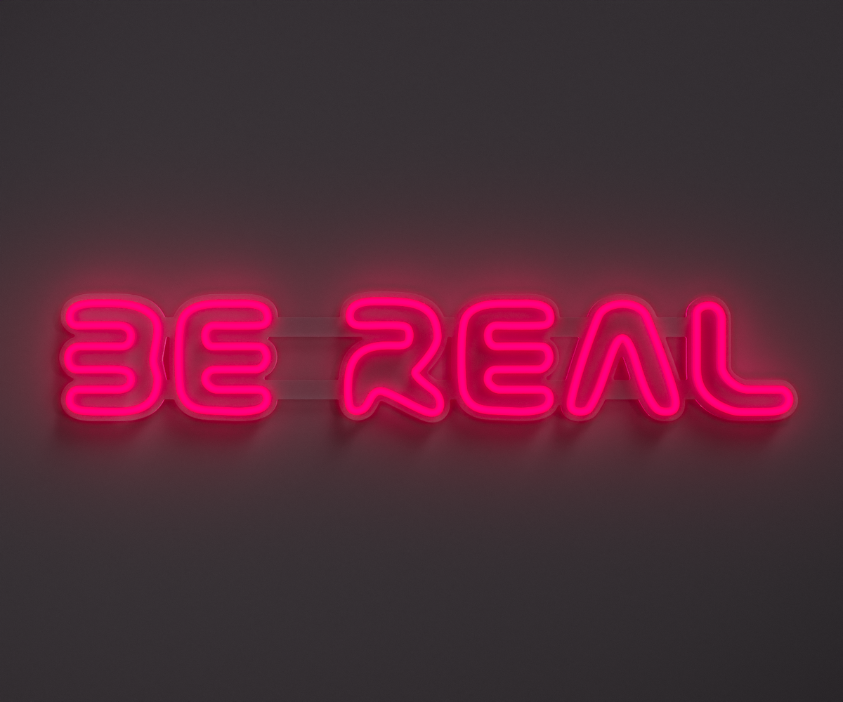 pink neon sign that says be real