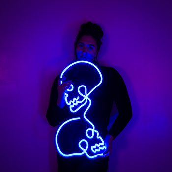 person holding a blue neon sign of two skulls