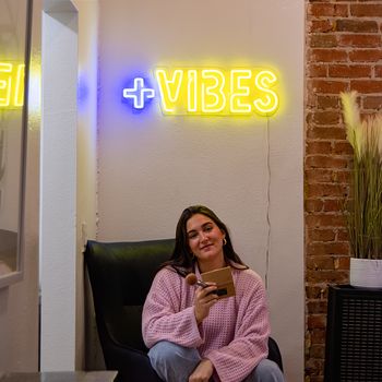 A girl with a yellow neon sign that says "Vibes" by Valoneon