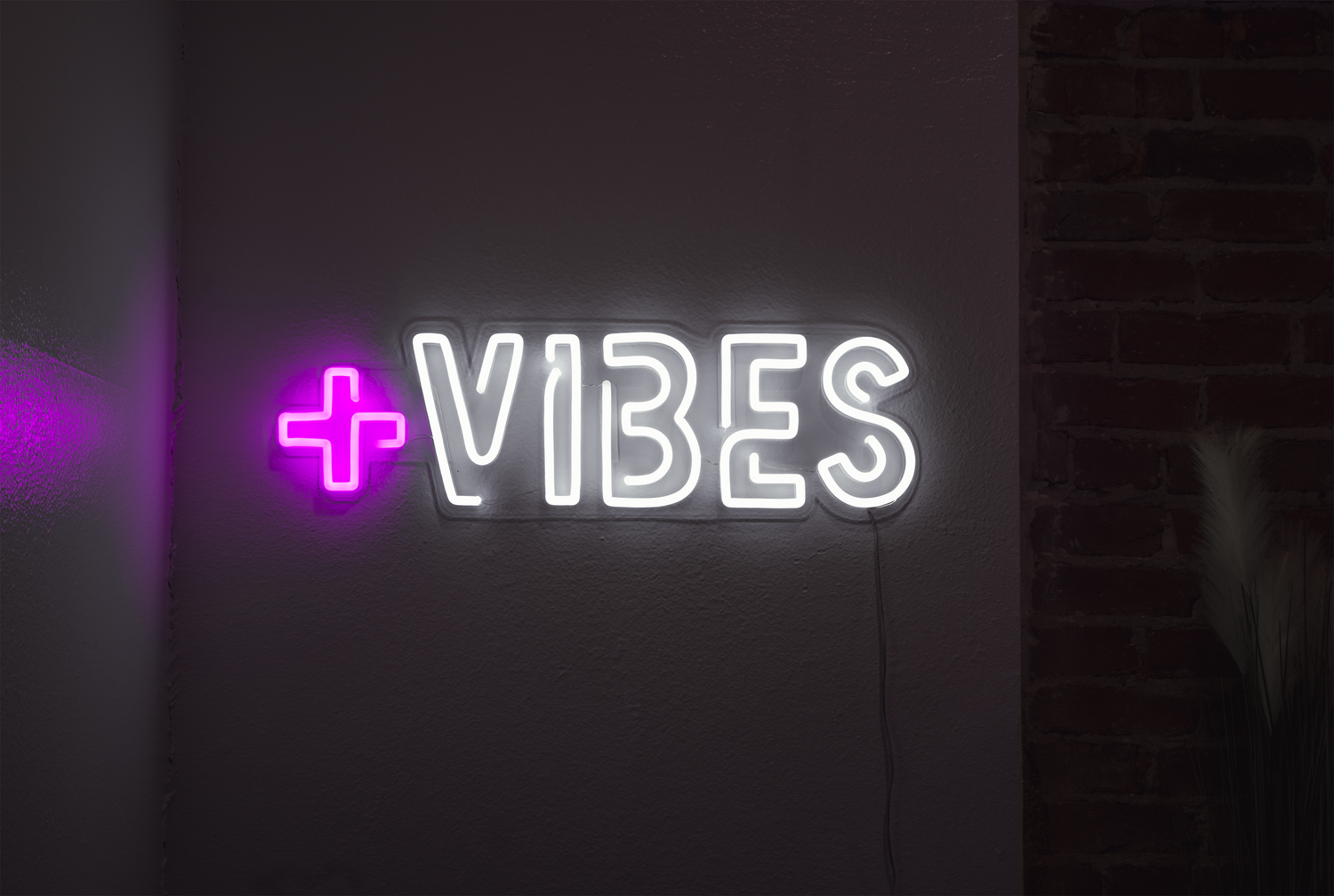 a white and pink 'positive vibes' neon sign in a bedroom