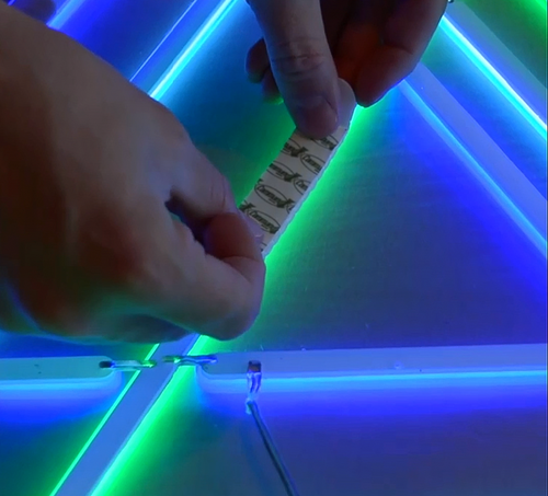 Applying adhesive strips to a neon sign